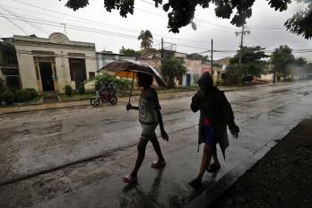 Personas se protegen de la lluvia este martes, en Santiago de Cuba (Cuba). EFE/ Ernesto Mastrascusa Personas se protegen de la lluvia este martes, en Santiago de Cuba (Cuba). EFE/ Ernesto Mastrascusa