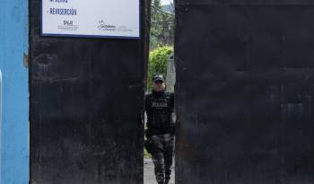 Miembro de la Policía Nacional Ecuatoriana cerrando la puerta del complejo penitenciaro Del Litoral.