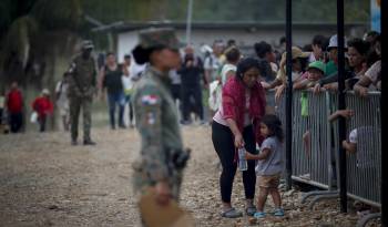 Una migrante con una niña esperan en una estación de recepción migratoria luego de cruzar la selva del Darién con rumbo a Estados Unidos.