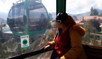 Una mujer viaja en una cabina del transporte por cable Mi Teleférico, el 27 de marzo de 2024 en La Paz (Bolivia).