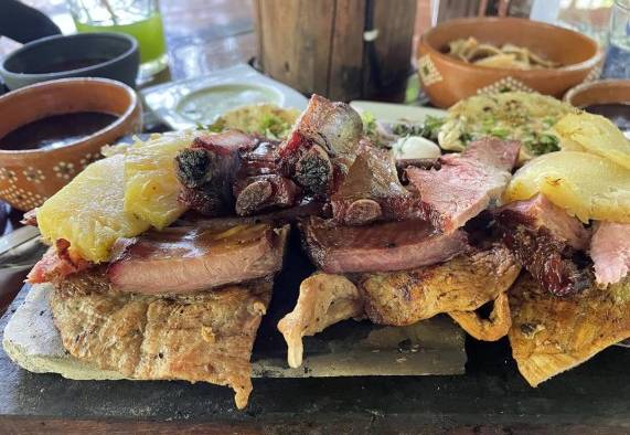 Vista de un platillo preparado con carne ahumada, longaniza y poc chuc servido sobre una tabla en el restaurante Achiote, poblado de Tikuch, Valladolid, estado de Yucatán (México). Vista de un platillo preparado con carne ahumada, longaniza y poc chuc servido sobre una tabla en el restaurante Achiote, poblado de Tikuch, Valladolid, estado de Yucatán (México).