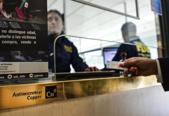 La policía personalizada revisa los pasaportes de viajeros que llegan a Chile, en un módulo protegido con cobre antimicrobiano en Santiago el 28 de agosto de 2016. La policía personalizada revisa los pasaportes de viajeros que llegan a Chile, en un módulo protegido con cobre antimicrobiano en Santiago el 28 de agosto de 2016.