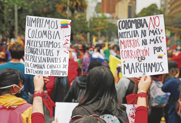 Una mujer sostiene dos carteles durante una movilización para rechazar la violencia ocurrida en las protestas del 6 de mayo en el Parque Nacional de Bogotá. Una mujer sostiene dos carteles durante una movilización para rechazar la violencia ocurrida en las protestas del 6 de mayo en el Parque Nacional de Bogotá.