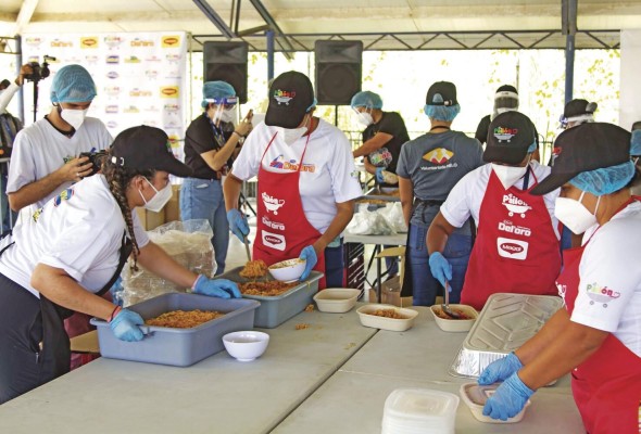 Voluntarios sirven los platos de arroz con pollo. Voluntarios sirven los platos de arroz con pollo.