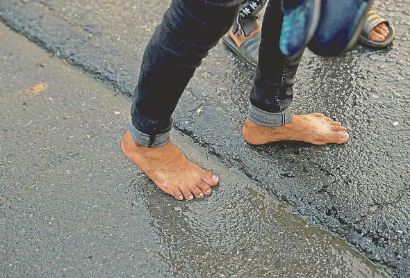 Manuel Rivera, un migrante de 19 años, camina descalzo para no mojar sus zapatos por la lluvia. Manuel Rivera, un migrante de 19 años, camina descalzo para no mojar sus zapatos por la lluvia.