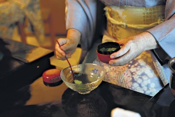 El té en polvo se coloca en el cuenco con una cucharilla de bambú El té en polvo se coloca en el cuenco con una cucharilla de bambú