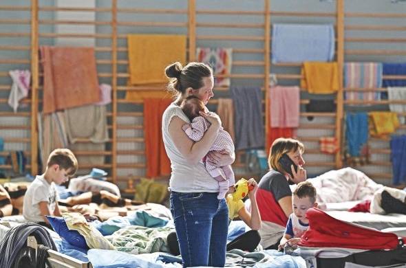 Una mujer sostiene a su bebé de dos meses en un refugio temporal ubicado en un gimnasio de una escuela secundaria en Przemysl, cerca de la frontera entre Ucrania y Polonia.