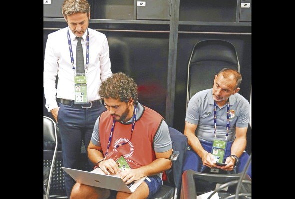 Escriu, sentado, junto al entrenador nacional Thomas Christiansen de pie, y Javi Sánchez Jara del cuerpo técnico, comparten información. Escriu, sentado, junto al entrenador nacional Thomas Christiansen de pie, y Javi Sánchez Jara del cuerpo técnico, comparten información.