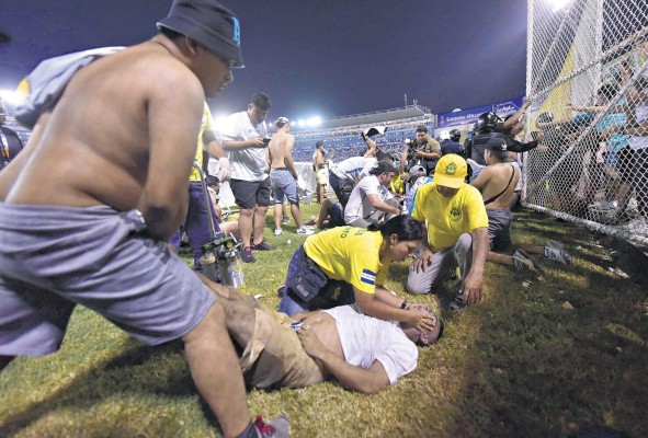 Fanáticos y personal de emergencia dan los primeros auxilios a los afectados. Fanáticos y personal de emergencia dan los primeros auxilios a los afectados.