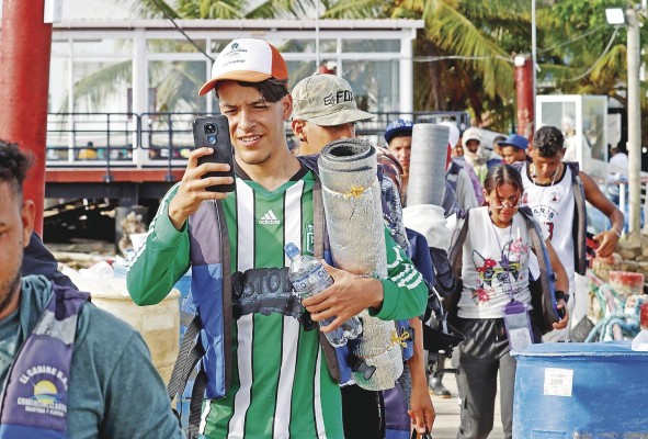 Migrantes usan sus celulares antes de abordar una lancha el 8 de octubre de 2022 en Necoclí. Migrantes usan sus celulares antes de abordar una lancha el 8 de octubre de 2022 en Necoclí.