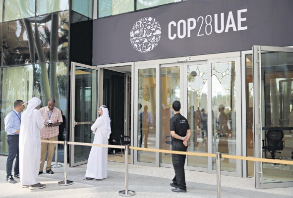 La gente espera afuera de un edificio decorado con el logotipo de la COP28 antes de la cumbre climática en Dubai. La gente espera afuera de un edificio decorado con el logotipo de la COP28 antes de la cumbre climática en Dubai.