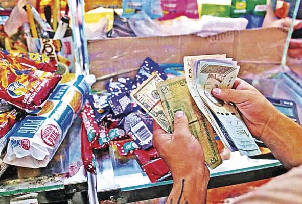 Un vendedor cuenta bolívares venezolanos y billetes de dólares estadounidenses en una tienda de comestibles en Caracas, en una imagen de archivo. Un vendedor cuenta bolívares venezolanos y billetes de dólares estadounidenses en una tienda de comestibles en Caracas, en una imagen de archivo.