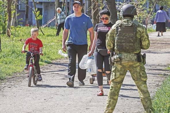 Fotografía de archivo muestra a personas caminando cerca de un soldado ruso que vigila las calles de Mariúpol, en la región separatista del este de Ucrania. Fotografía de archivo muestra a personas caminando cerca de un soldado ruso que vigila las calles de Mariúpol, en la región separatista del este de Ucrania.