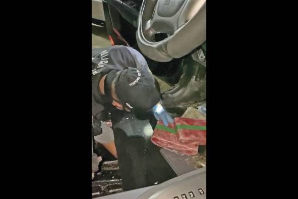 Agentes policiales extraen la droga del auto. Agentes policiales extraen la droga del auto.