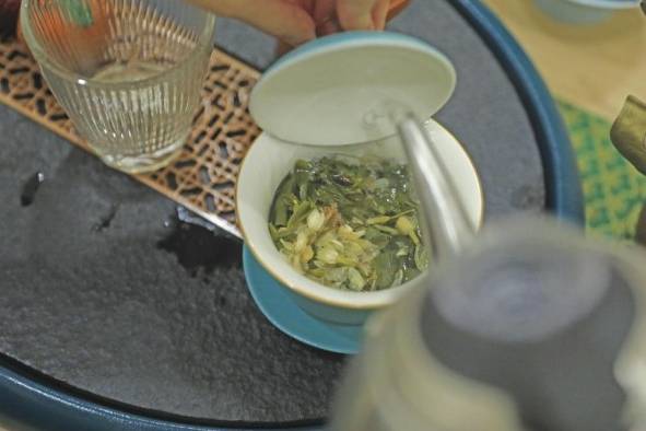 El agua caliente se vierte en la tapa del gaiwan para que caiga suavemente sobre las hojas de té. El agua caliente se vierte en la tapa del gaiwan para que caiga suavemente sobre las hojas de té.