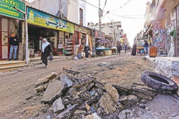 Palestinos caminan junto a los daños en una calle después de una incursión israelí en el campo de refugiados de Balata, Cisjordania. Palestinos caminan junto a los daños en una calle después de una incursión israelí en el campo de refugiados de Balata, Cisjordania.