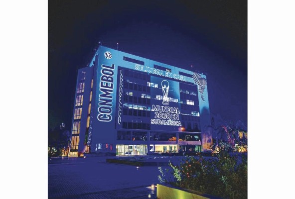 El edificio de la sede de la Conmebol en Asunción, Paraguay, celebró el otorgamiento de tres partidos inaugurales en 2030 con una iluminación alusiva. El edificio de la sede de la Conmebol en Asunción, Paraguay, celebró el otorgamiento de tres partidos inaugurales en 2030 con una iluminación alusiva.
