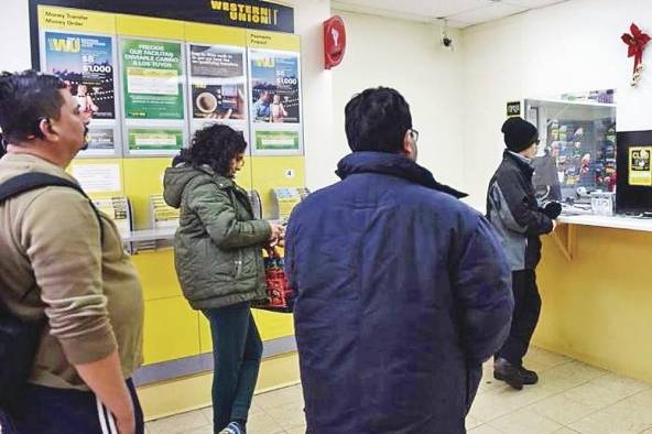 Varias personas esperan su turno para enviar dinero. Varias personas esperan su turno para enviar dinero.