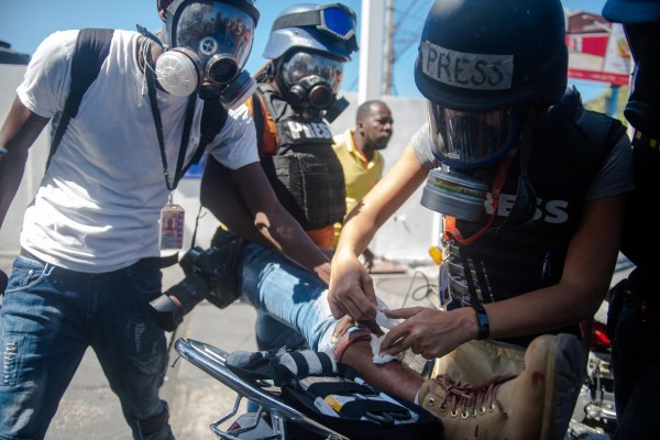 Una periodista extranjera da prímeros auxilios a un fotoperiodista herido en una protesta en Puerto Príncipe (Haití). Una periodista extranjera da prímeros auxilios a un fotoperiodista herido en una protesta en Puerto Príncipe (Haití).