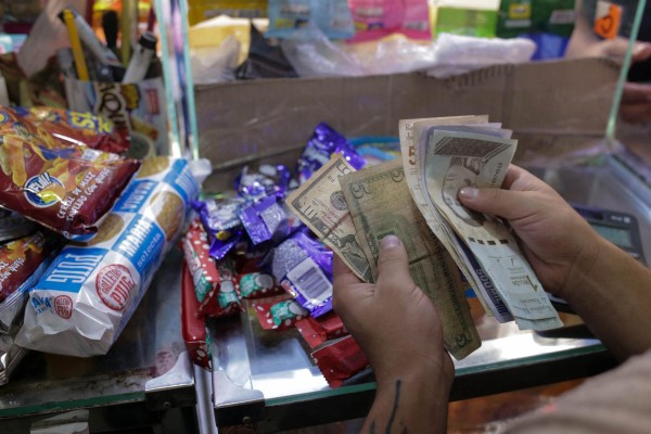 Un vendedor cuenta bolívares venezolanos y billetes de dólares estadounidenses en una tienda de comestibles en Caracas, en una imagen de archivo. Un vendedor cuenta bolívares venezolanos y billetes de dólares estadounidenses en una tienda de comestibles en Caracas, en una imagen de archivo.