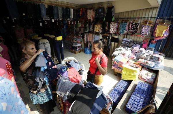 Una mujer muestra prendas de vestir a una clienta en una tienda de ropa, el 18 de abril de 2023, en el centro de San Salvador Una mujer muestra prendas de vestir a una clienta en una tienda de ropa, el 18 de abril de 2023, en el centro de San Salvador