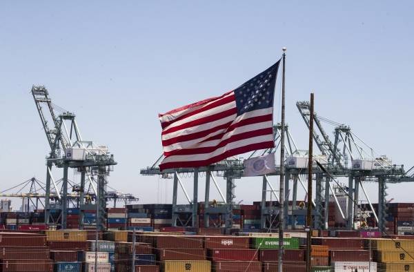 Una bandera de EE. UU. sobre barcos de conetenedores en Los Angeles, California, en una fotografía de archivo. Una bandera de EE. UU. sobre barcos de conetenedores en Los Angeles, California, en una fotografía de archivo.