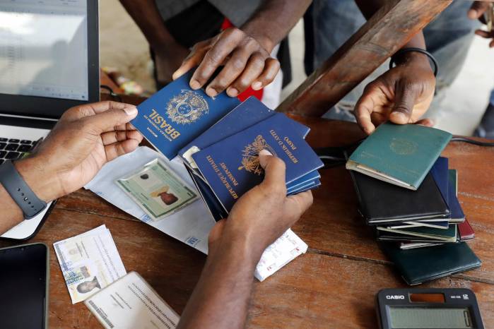 Fotografía de archivo de una persona mientras recibe pasaportes de migrantes de diversas partes del mundo que compran tiquetes para Capurganá, en el embarcadero de Necoclí (Colombia). Fotografía de archivo de una persona mientras recibe pasaportes de migrantes de diversas partes del mundo que compran tiquetes para Capurganá, en el embarcadero de Necoclí (Colombia).