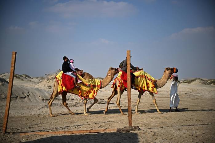 La gente monta en camello por las dunas del desierto de Al Wakrah, al sur de Doha, en una imagen de archivo. La gente monta en camello por las dunas del desierto de Al Wakrah, al sur de Doha, en una imagen de archivo.