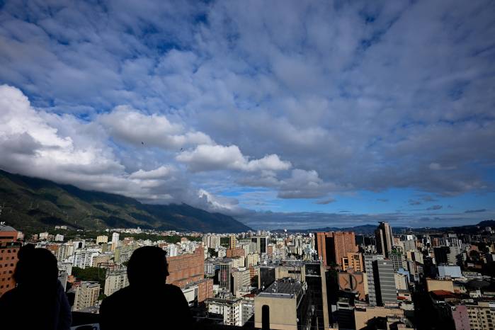 La gente en una cafetería conversa mientras disfruta de la vista de la ciudad de Caracas. La gente en una cafetería conversa mientras disfruta de la vista de la ciudad de Caracas.
