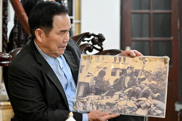 Esta foto, tomada el 11 de marzo de 2025, muestra a Ngo Sy Nguyen, ex artillero principal del Tanque 390, sosteniendo una fotografía tomada después de que su tanque atravesara las puertas del palacio presidencial de Saigón el 30 de abril de 1975, durante una entrevista en su casa en Hanói. Esta foto, tomada el 11 de marzo de 2025, muestra a Ngo Sy Nguyen, ex artillero principal del Tanque 390, sosteniendo una fotografía tomada después de que su tanque atravesara las puertas del palacio presidencial de Saigón el 30 de abril de 1975, durante una entrevista en su casa en Hanói.