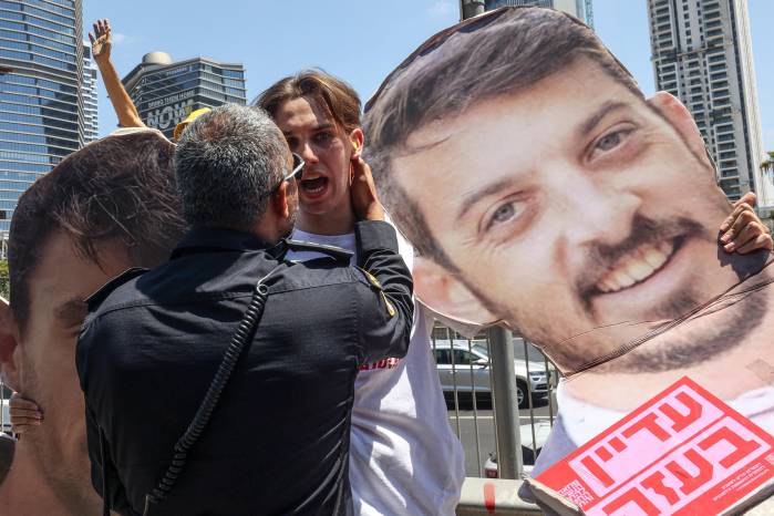 Un miembro de las fuerzas de seguridad israelíes se enfrenta con un manifestante que sostiene una silueta de un rehén, durante una protesta antigubernamental en Tel Aviv. Un miembro de las fuerzas de seguridad israelíes se enfrenta con un manifestante que sostiene una silueta de un rehén, durante una protesta antigubernamental en Tel Aviv.