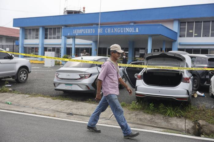 Una persona camina frente a algunos vehículos vandalizados en la entrada del aeropuerto de Changuinola este viernes, en Changuinola (Panamá). Una persona camina frente a algunos vehículos vandalizados en la entrada del aeropuerto de Changuinola este viernes, en Changuinola (Panamá).