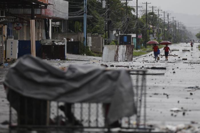 Personas caminan por una via afectada por las manifestaciones este sábado, en Changuinola en Bocas del Toro (Panamá). Personas caminan por una via afectada por las manifestaciones este sábado, en Changuinola en Bocas del Toro (Panamá).