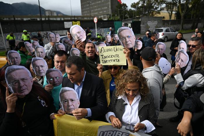 Partidarios del expresidente colombiano Álvaro Uribe portan máscaras con su rostro mientras esperan el veredicto de su juicio frente al Complejo Judicial de Paloquemao en Bogotá el 28 de julio de 2025. Partidarios del expresidente colombiano Álvaro Uribe portan máscaras con su rostro mientras esperan el veredicto de su juicio frente al Complejo Judicial de Paloquemao en Bogotá el 28 de julio de 2025.