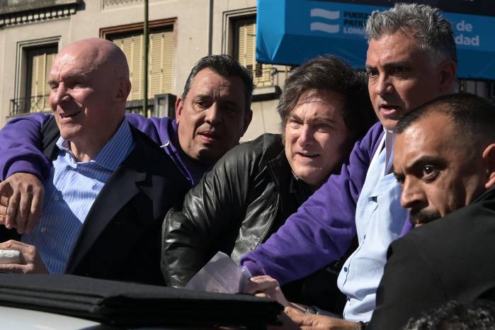 Milei (centro) reacciona junto al candidato a diputado del partido gobernante, José Luis Espert (izq.), y personal de seguridad, mientras manifestantes les lanzan objetos durante una caravana en Lomas de Zamora. Milei (centro) reacciona junto al candidato a diputado del partido gobernante, José Luis Espert (izq.), y personal de seguridad, mientras manifestantes les lanzan objetos durante una caravana en Lomas de Zamora.