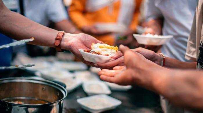 Voluntarios dan comida a personas que carecen de alimentos. Voluntarios dan comida a personas que carecen de alimentos.