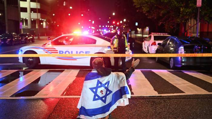 Una mujer ora con la bandera de Israel sobre sus hombros en el lugar donde se dio el crimen de dos empleados de la embajada de Israel en Estados Unidos. Una mujer ora con la bandera de Israel sobre sus hombros en el lugar donde se dio el crimen de dos empleados de la embajada de Israel en Estados Unidos.