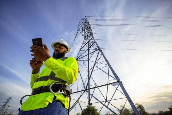 Fotografía sin fecha específica de toma cedida por T-Mobile que muestra a una persona observando su teléfono frente a una torre eléctrica en Estados Unidos. Fotografía sin fecha específica de toma cedida por T-Mobile que muestra a una persona observando su teléfono frente a una torre eléctrica en Estados Unidos.