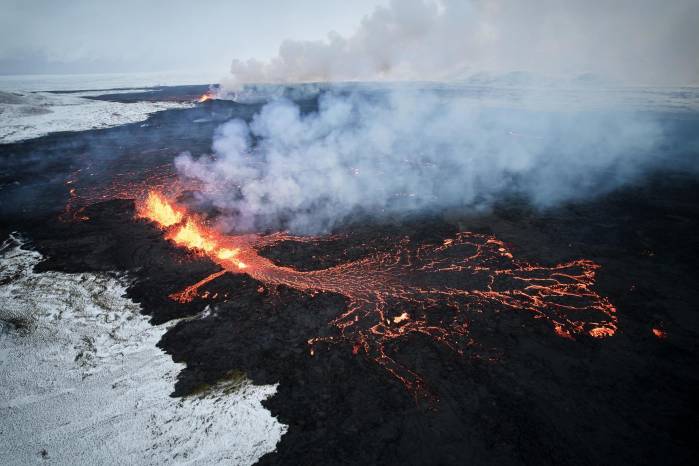Fotografía aérea tomada con un drone muestra lava y humo saliendo de una fisura volcánica durante una erupción cerca de la ciudad de Grindavik, en la península de Reykjanes (Islandia). Fotografía aérea tomada con un drone muestra lava y humo saliendo de una fisura volcánica durante una erupción cerca de la ciudad de Grindavik, en la península de Reykjanes (Islandia).