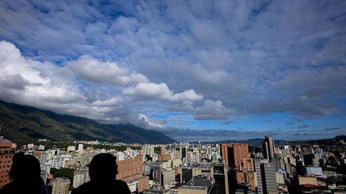 La gente en una cafetería conversa mientras disfruta de la vista de la ciudad de Caracas. La gente en una cafetería conversa mientras disfruta de la vista de la ciudad de Caracas.