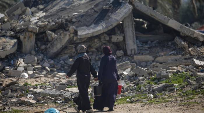 Mujeres palestinas desplazadas caminan frente a las ruinas de un edificio en Deir Al Blah, al sur de la franja de Gaza. Mujeres palestinas desplazadas caminan frente a las ruinas de un edificio en Deir Al Blah, al sur de la franja de Gaza.