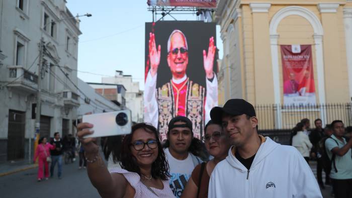 Personas toman una fotografía con la imagen del papa León XIV de fondo en la plaza central de Chiclayo (Perú). Personas toman una fotografía con la imagen del papa León XIV de fondo en la plaza central de Chiclayo (Perú).