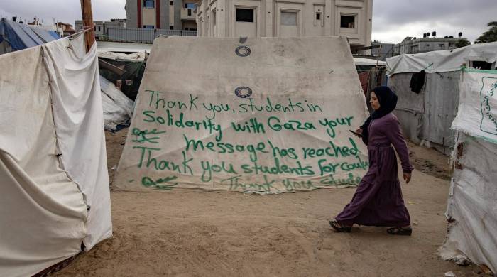 Una refugiada en Gaza pasa por delante de una inscripción de agradecimiento por las manifestaciones propalestinas en las universidades norteamericanas. Una refugiada en Gaza pasa por delante de una inscripción de agradecimiento por las manifestaciones propalestinas en las universidades norteamericanas.