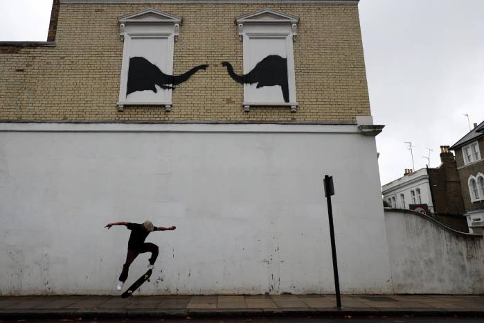 Un hombre en una patineta bajo la nueva obra del artista callejero británico, Banksy. Un hombre en una patineta bajo la nueva obra del artista callejero británico, Banksy.