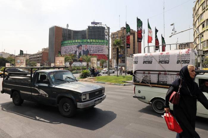 Los automovilistas pasan con sus vehículos junto a una valla publicitaria que representa al líder supremo de Irán, el ayatolá Ali Jamenei, colocada en el centro de la plaza Valiasr de Teherán, el 13 de julio de 2025. Los automovilistas pasan con sus vehículos junto a una valla publicitaria que representa al líder supremo de Irán, el ayatolá Ali Jamenei, colocada en el centro de la plaza Valiasr de Teherán, el 13 de julio de 2025.