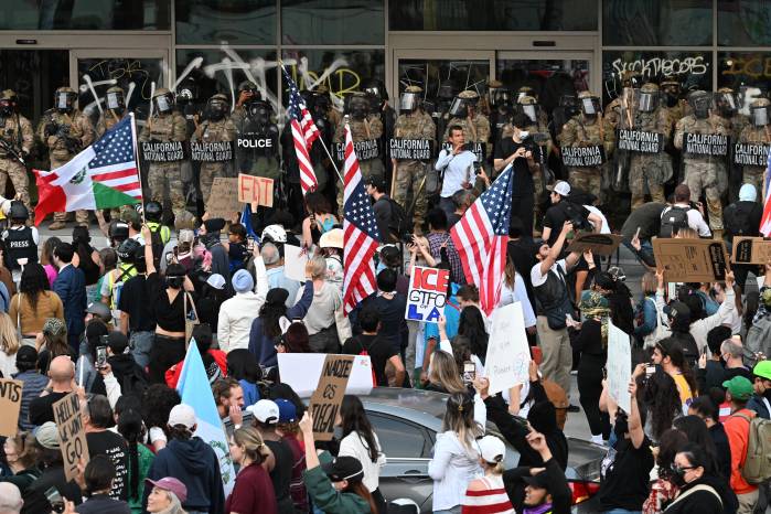 La Guardia Nacional de California y la Oficina de Aduanas y Protección Fronteriza de EE. UU. observan a los manifestantes congregados frente al Edificio Federal antes de la entrada en vigor del toque de queda. La Guardia Nacional de California y la Oficina de Aduanas y Protección Fronteriza de EE. UU. observan a los manifestantes congregados frente al Edificio Federal antes de la entrada en vigor del toque de queda.