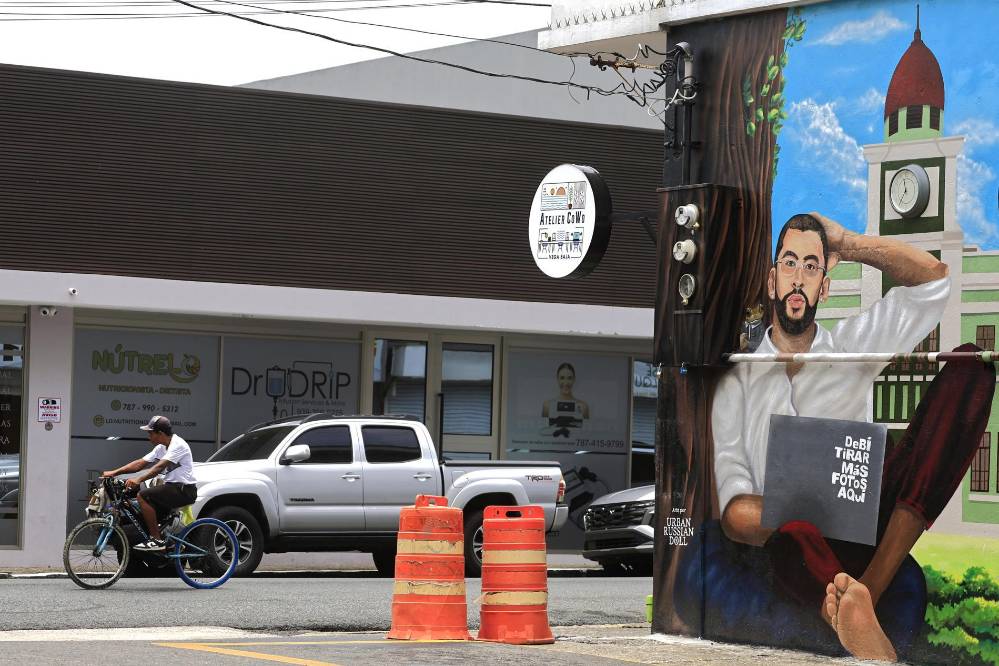 Una persona pasa en bicicleta frente a un mural de Bad Bunny.