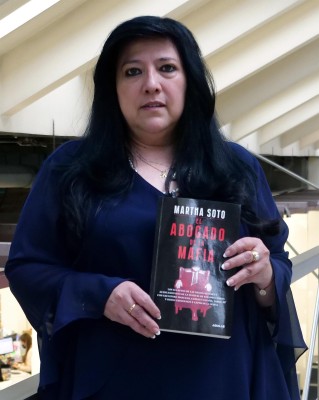 Fotografía cedida por Laura Morales que muestra a la periodista colombiana Martha Soto mientras posa para la foto con su libro El Abogado de la Mafía, en Bogotá
