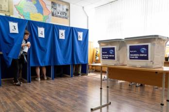 A Moldovan woman walks out of a booth to cast her ballot for the European Parliament elections, at a polling station in Chisinau on June 9, 2024.