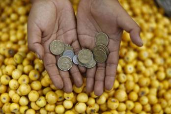 Fotografía de archivo en donde una vendedora de frutas muestra unas monedas en la central de abastos La Tiendona en San Salvador.
